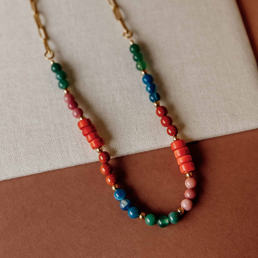Studio shot of the Phoebe Gemstone Necklace laid across a linen surface highlighting the rich bead colors.