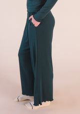 Close-up view of a hand in the side slit pocket of the dark green Poplinen Hedy Ribbed Modal Lounge Pant.
