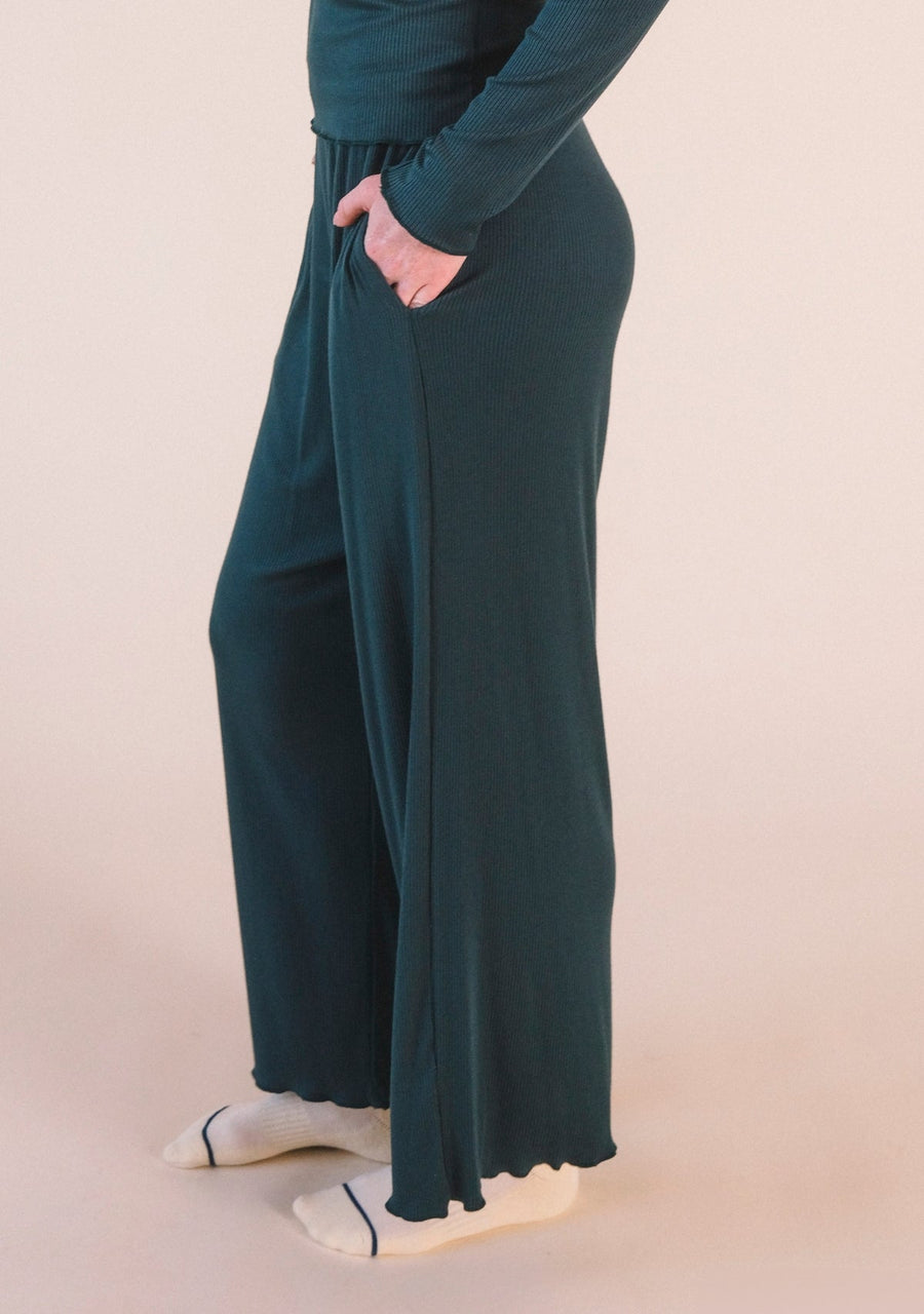 Close-up view of a hand in the side slit pocket of the dark green Poplinen Hedy Ribbed Modal Lounge Pant.
