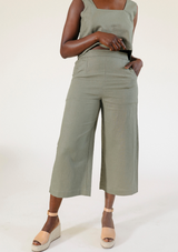 Front view of a model wearing the olive green Poplinen Nin Linen Pant with a matching cropped top and wedge sandals.