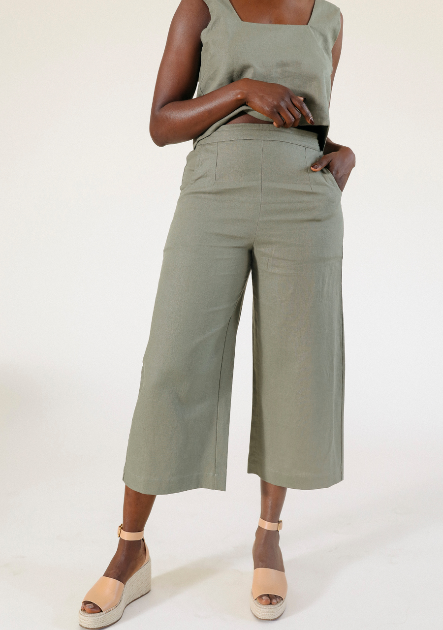 Front view of a model wearing the olive green Poplinen Nin Linen Pant with a matching cropped top and wedge sandals.