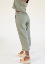 Rear angle view highlighting the cinched elastic back waistband and drape of the Poplinen Nin Linen Pant in Olive.