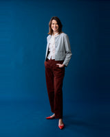 Viva Voce CEO Amy wearing the Reistor Lady Jacket in Grey Cotton Tweed against a blue backdrop.