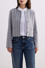 Full-length front view of model wearing the grey cotton tweed Reistor Lady Jacket buttoned up with straight-leg denim jeans.