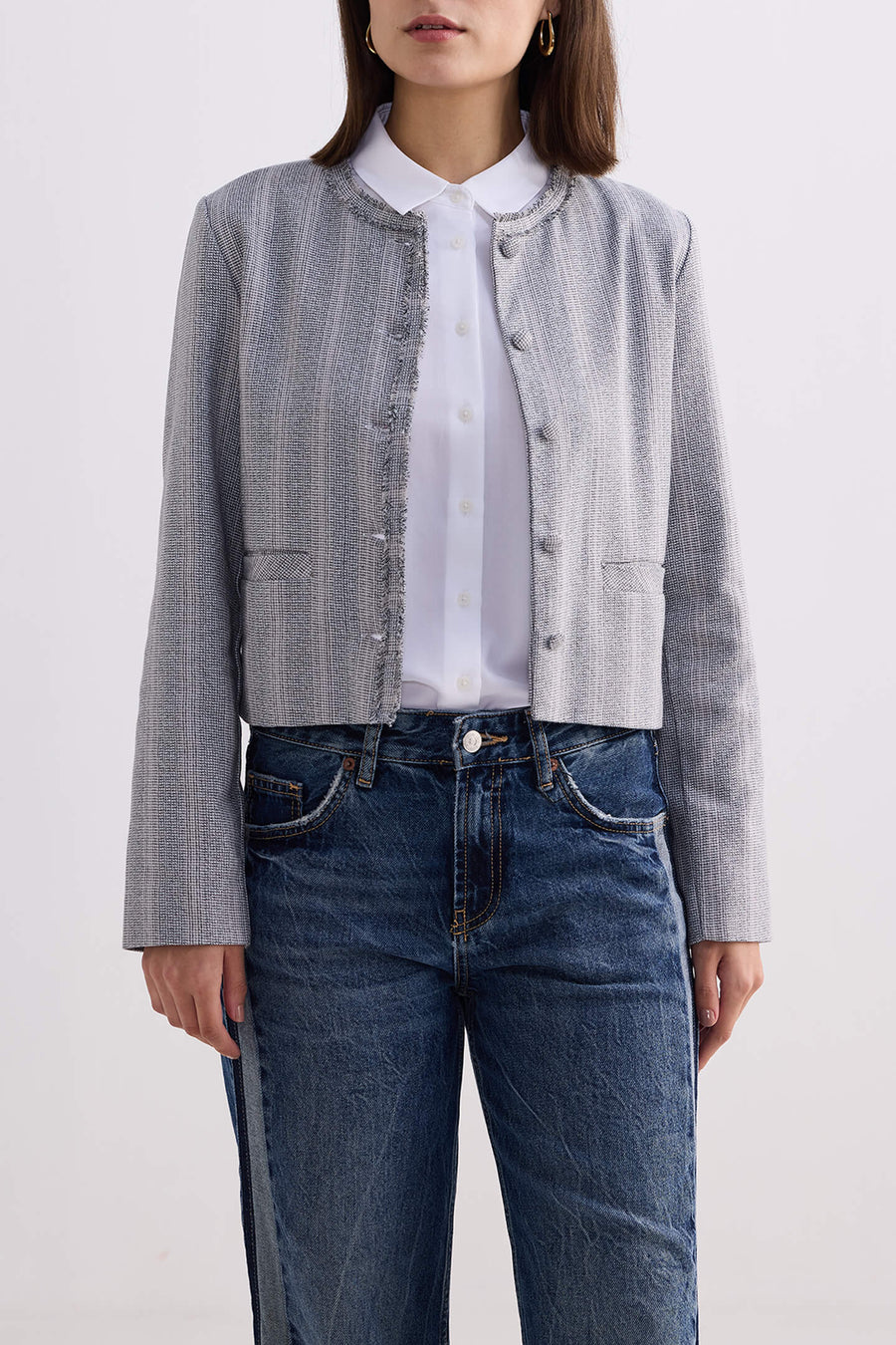 Full-length front view of model wearing the grey cotton tweed Reistor Lady Jacket buttoned up with straight-leg denim jeans.