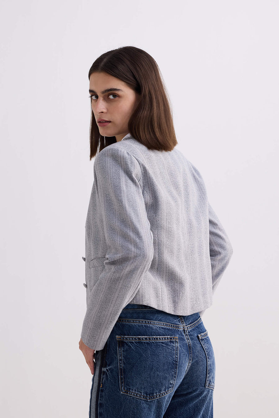 Side profile and back view of model wearing the Reistor Lady Jacket in Grey Cotton Tweed looking over her shoulder.