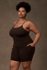 Side angle of a model demonstrating the functional deep side leg pocket on the cocoa brown Reprise Activewear Sage Shorts.