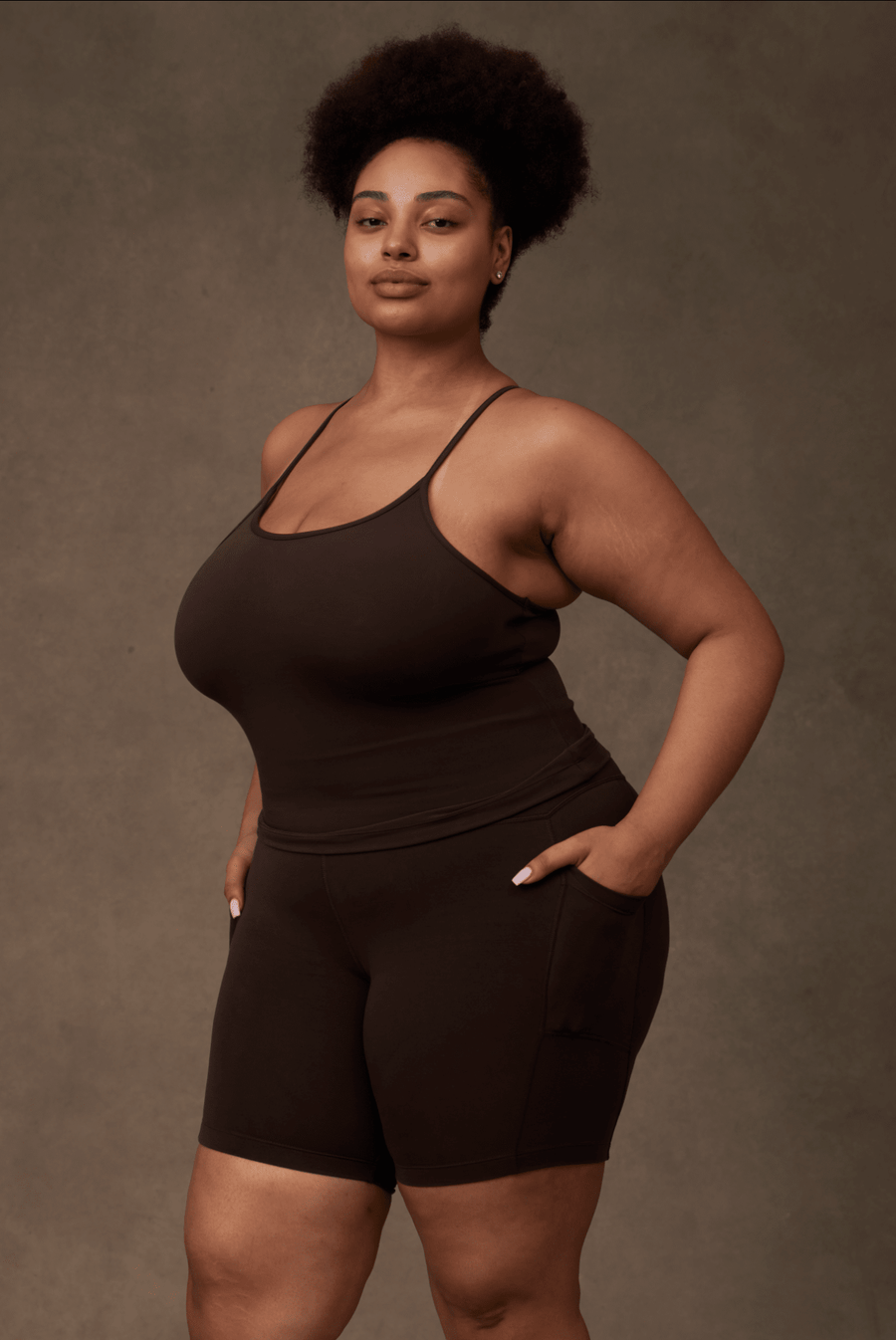 Side angle of a model demonstrating the functional deep side leg pocket on the cocoa brown Reprise Activewear Sage Shorts.