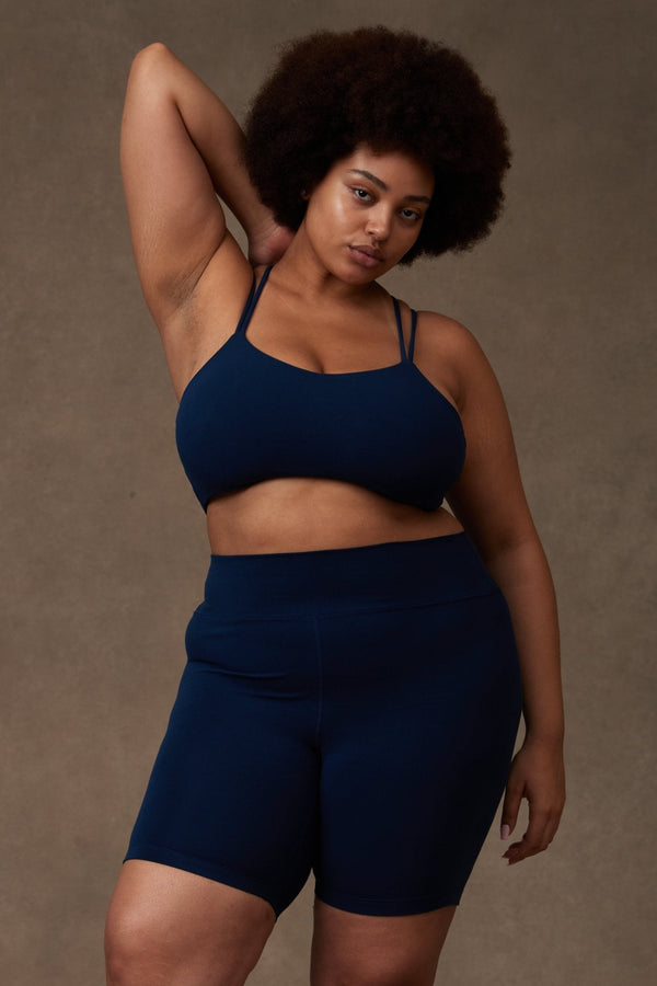Plus-size model wearing the sapphire blue Reprise Activewear high-rise Sage Pocket Shorts with matching bra.