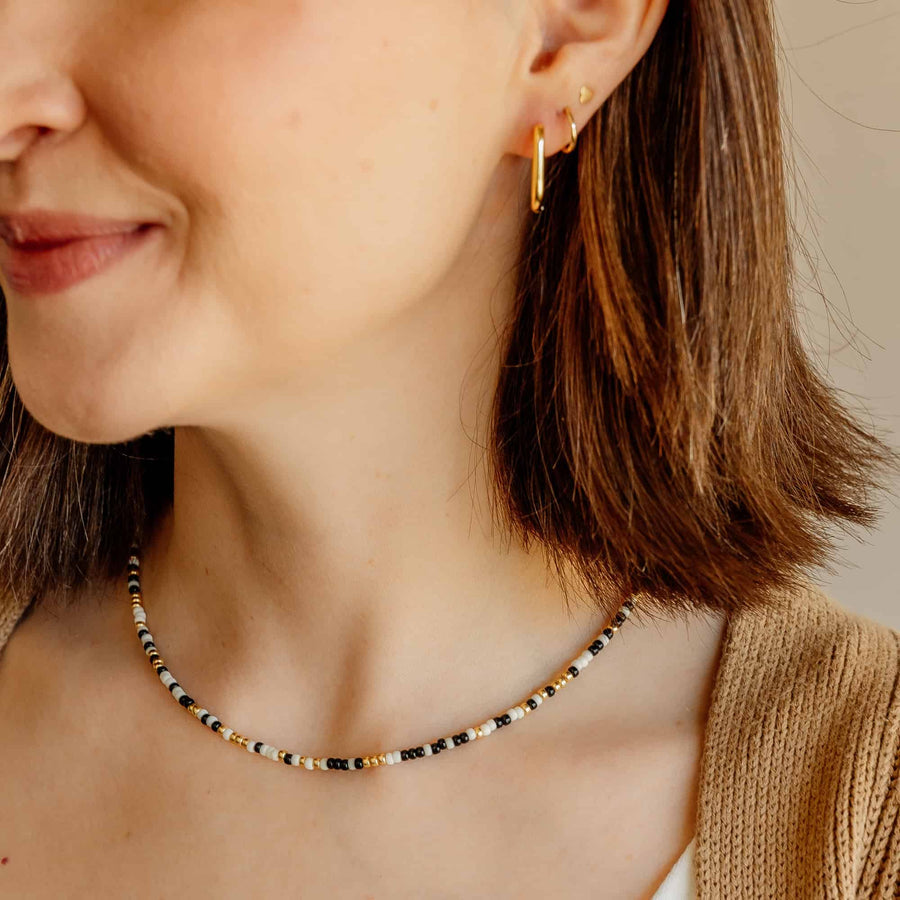 Model wearing the gold Sela Designs Rectangle Everyday Hoop Earring styled alongside a delicate beaded necklace.