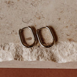 Pair of tarnish-free silver-plated Sela Designs Rectangle Everyday Hoop Earrings displayed on stone.