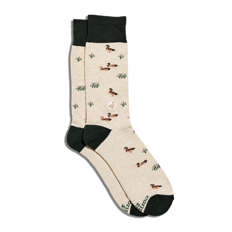 Studio flat lay shot of Conscious Step Socks That Protect Ducks displaying the green and beige mallard duck print with dark green heels and toes.