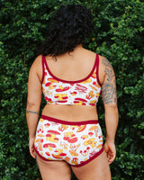 Back view showing the broad back coverage and red contrast trim of the Thunderpants USA Longline Bra on model Crosby.