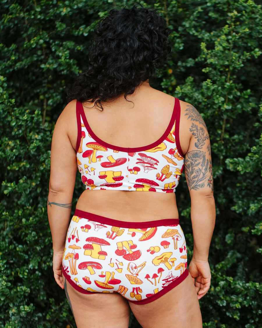 Back view showing the broad back coverage and red contrast trim of the Thunderpants USA Longline Bra on model Crosby.