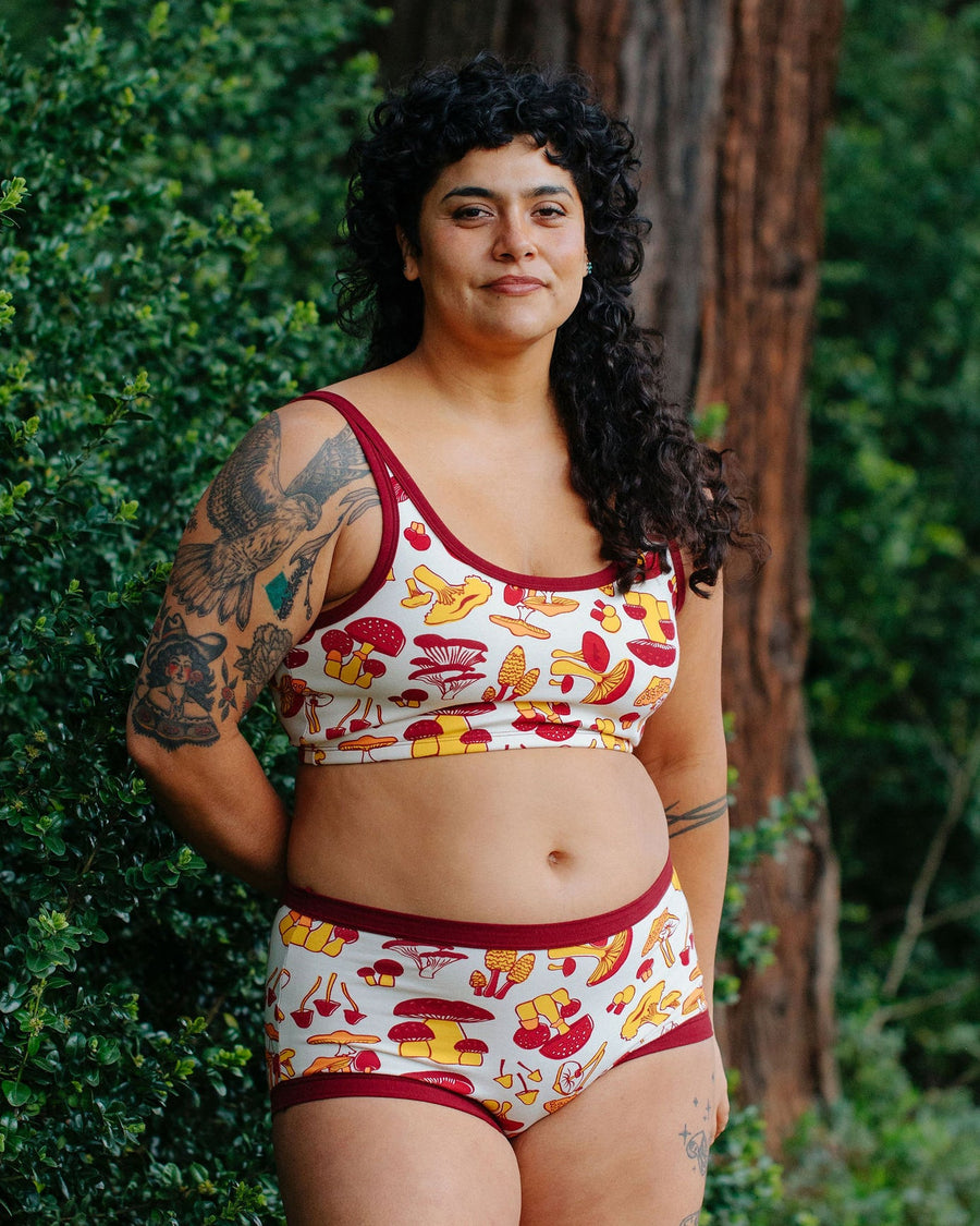 Full-length front view of model Crosby wearing the Thunderpants USA Longline Bra in size 2XL mushroom print styled with matching underwear.