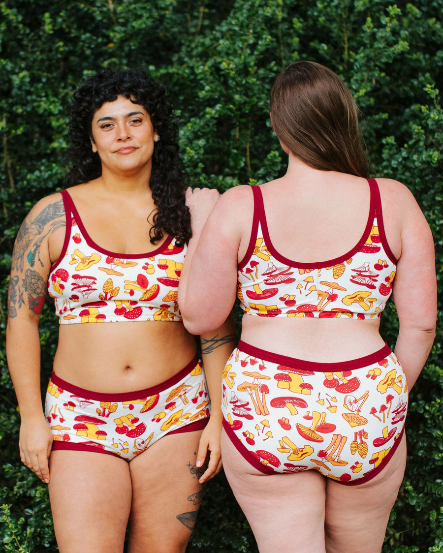 Two models standing outdoors wearing the Thunderpants USA Longline Bra and matching underwear in mushroom print, showing front and back views.