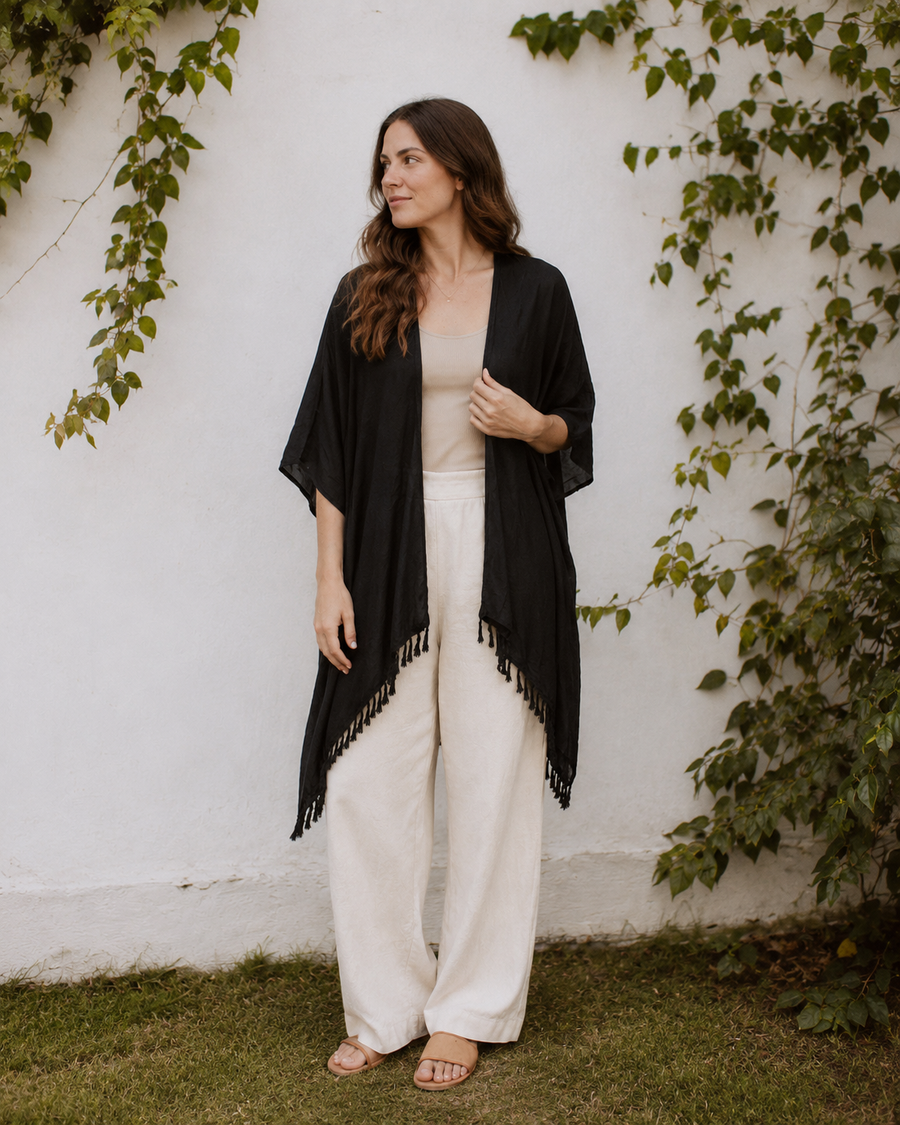 Model wearing the black Village Thrive Rayon Kimono with fringe detailing styled over a neutral outfit.
