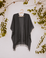 Dark charcoal grey Village Thrive Rayon Kimono with fringe hem on a hanger against a white background.