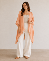 Model in Peach Village Thrive Rayon Kimono with tassel fringe hem holding the lapel.
