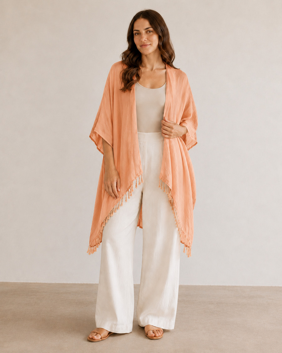 Model in Peach Village Thrive Rayon Kimono with tassel fringe hem holding the lapel.