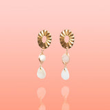 Pair of Tribe and Temple Paloma dangle earrings featuring gold oval posts, wire-wrapped light pink jade stones, and white teardrop shell pendants.